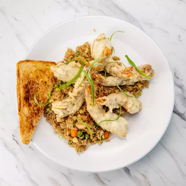 Tempura shrimp and fried rice with green onions and a slice of toast on a white plate.